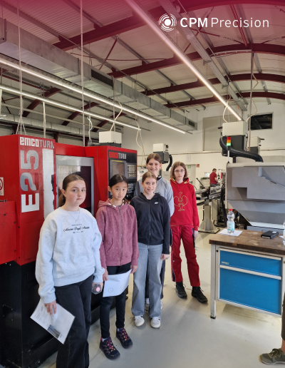 Group of girls standing in a production hall next to CNC machines, holding worksheets during a Girls’ Day visit to CPM Precision.